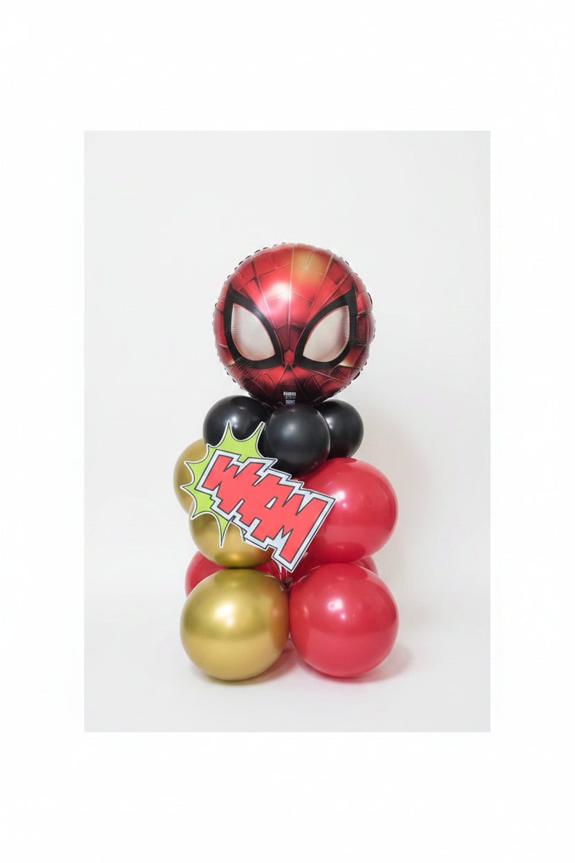 A Spider-Man themed balloon stack centerpiece featuring a red and black Spider-Man head balloon, black and red balloons, gold balloons, and a 'POW!' comic starburst sign, set against a glittery gold backdrop.